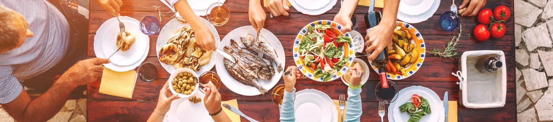 Big family have a dinner with fresh cooked meal on open garden terrace